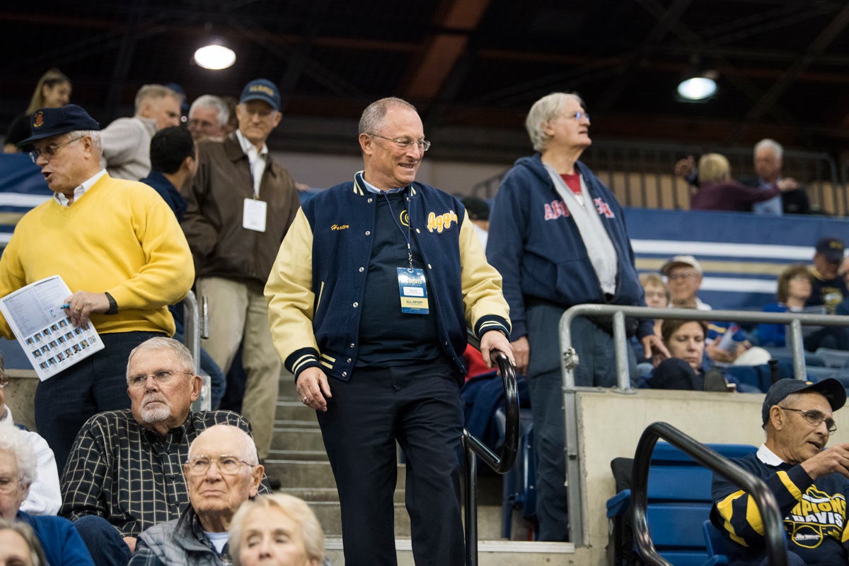 Ralph J. Hexter, in Aggie jacket, walks down basketball bleachers.