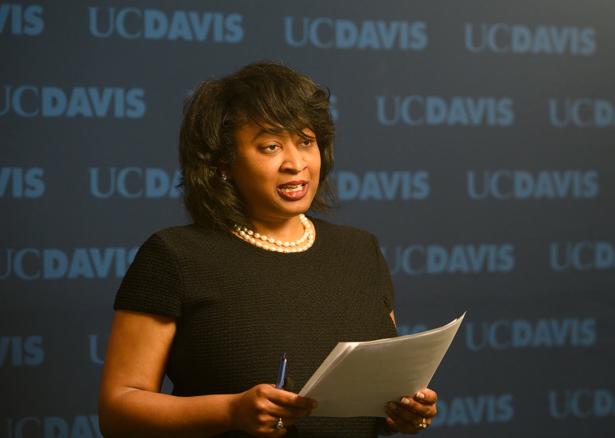 Renetta Garrison Tull reading remarks, against "UC Davis" backdrop in broadcast studio.