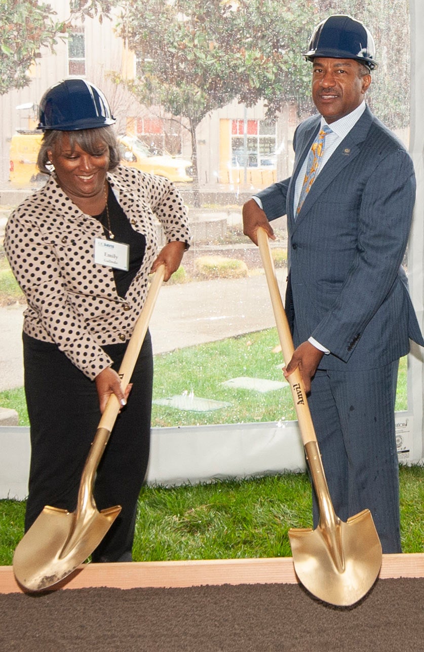 Emily Galinod and Chancellor Gary S. May, in hard hats, weild gold shovels at student housing groundbreaking.