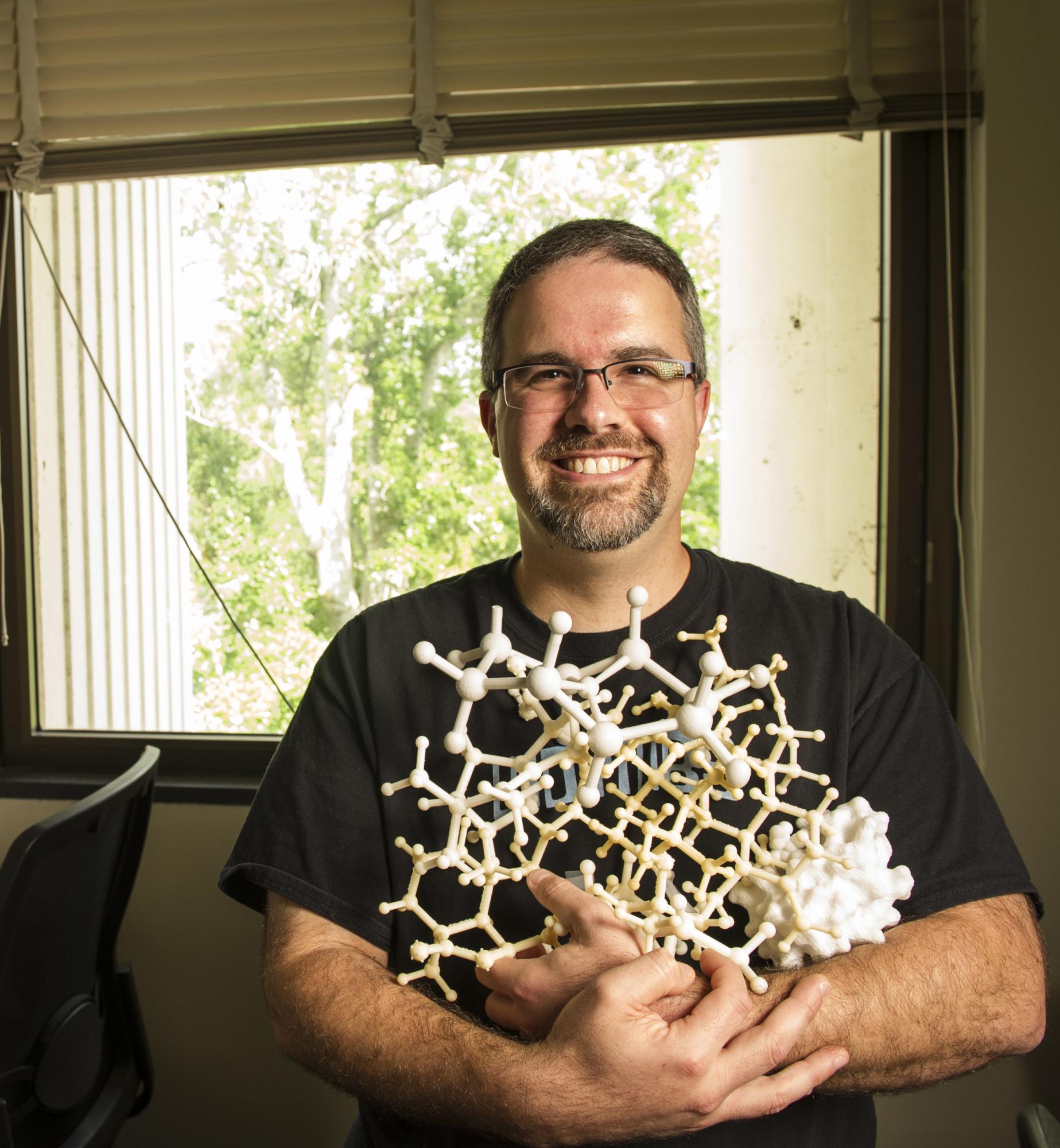 A male profesor holds 3-D models used in chemistry