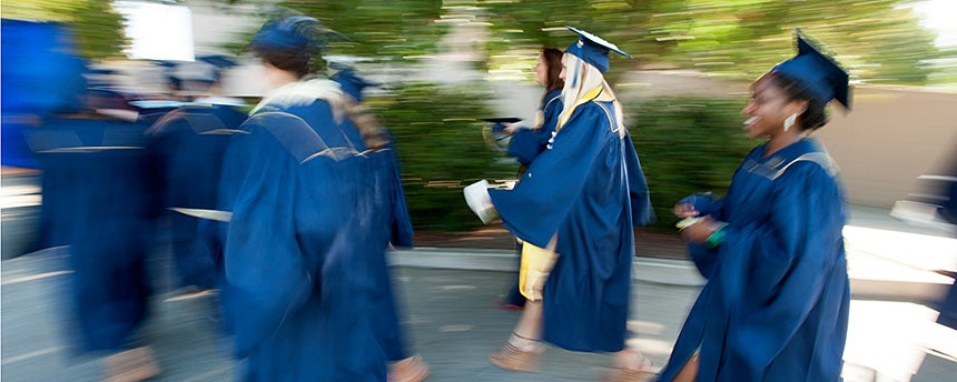 Students in graduation caps and gowns walking