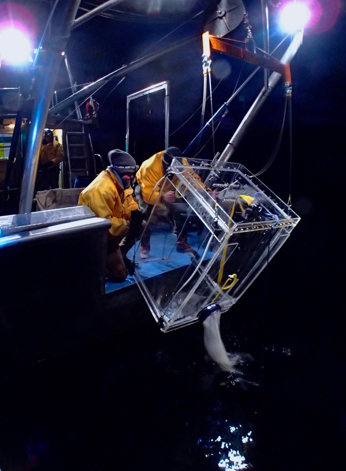 Two scientists bring in cage while trawling for mysis shrimp at night at Lake Tahoe