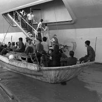 Vietnamese refugees in a small boat being loaded onto a U.S. amphibious command ship in 1982. 
