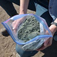 Researcher holds bag of rock dust to be added to agricultural soils. 
