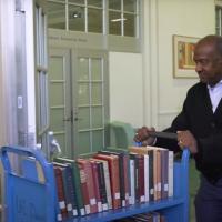 Chancellor May in the library pushing a book cart