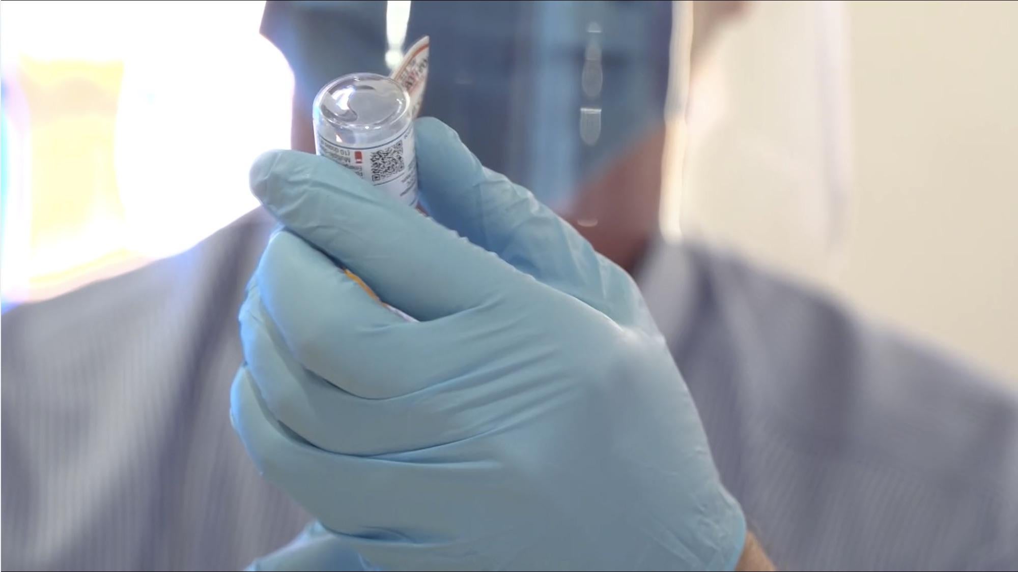 technician in mask examines syringe at UC Davis