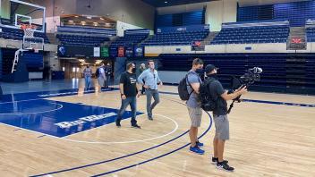 Host Alex and film crew looking at the University Credit Union Center