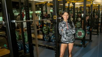 A student poses against a row of squat racks