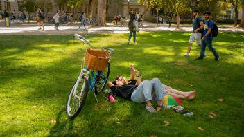 Two students lay on the grass of the UC Davis quad 