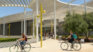Students ride their bicycles past the Manetti Shrem Museum of Art at UC Davis