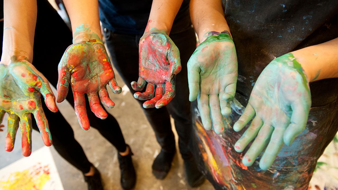 Art studio majors show their hands after painting with acrylics.