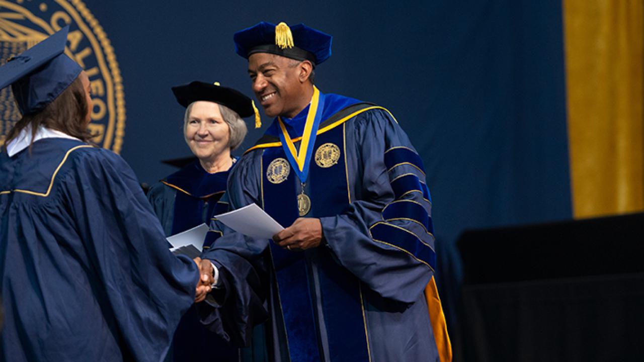 Chancellor Gary May shakes hands as student cross the stage for commencement.
