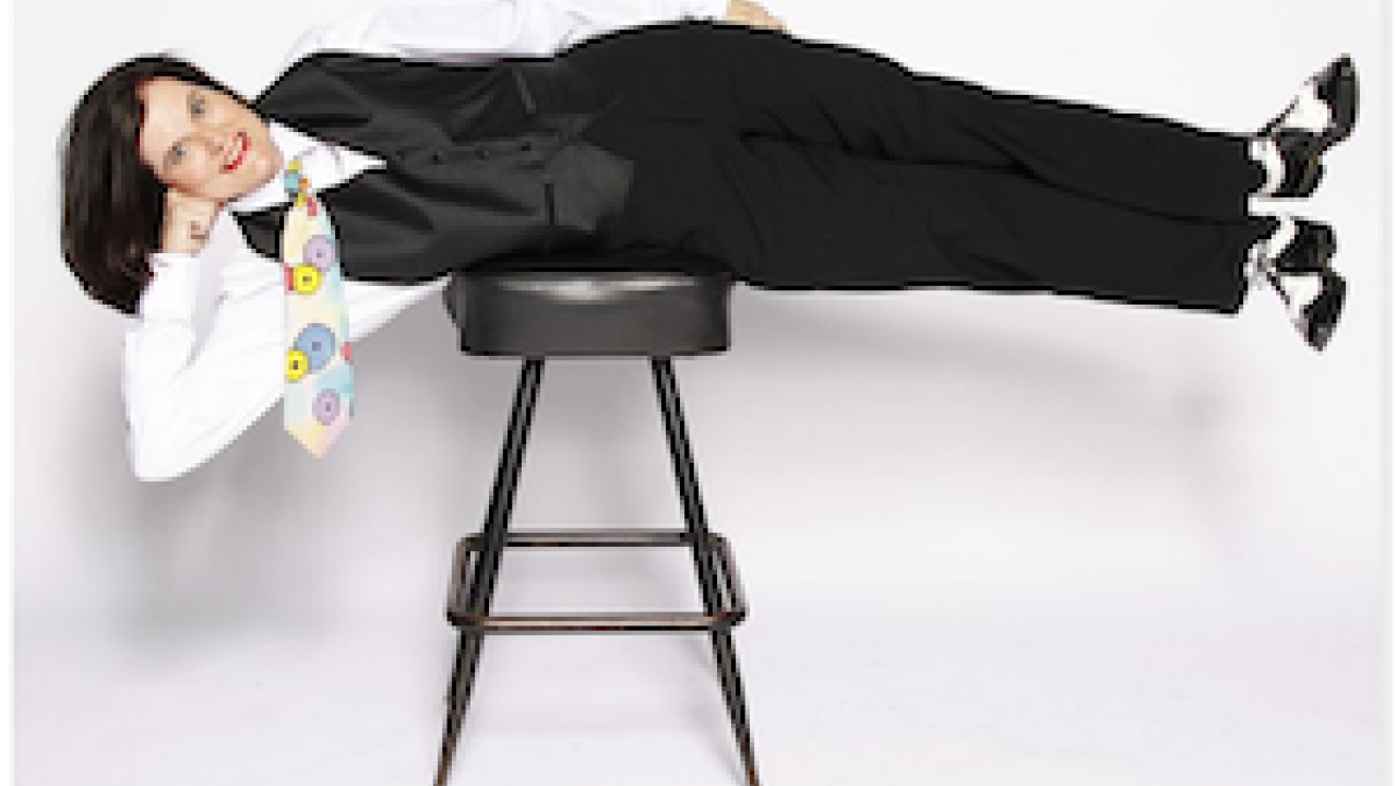 Paula Poundstone lying horizontally on a stool.