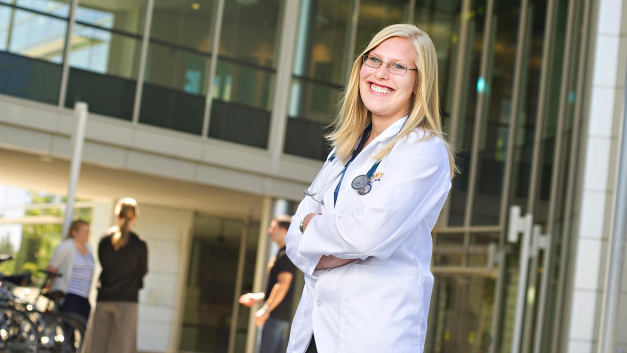 Biolology alumna Kate Brown Richards posing in her doctor's coat at UC Davis Medical Center