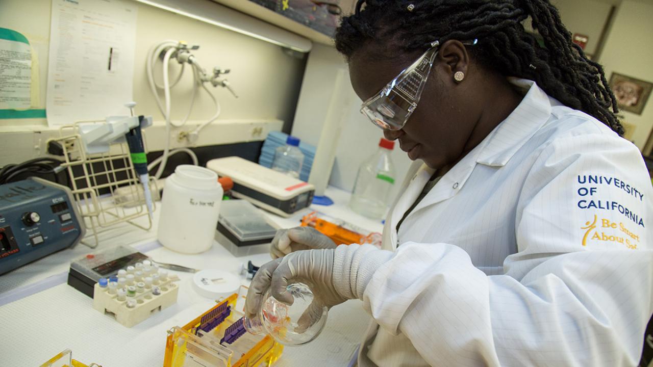 Female student in lab gear working on an experiment to separate DNA