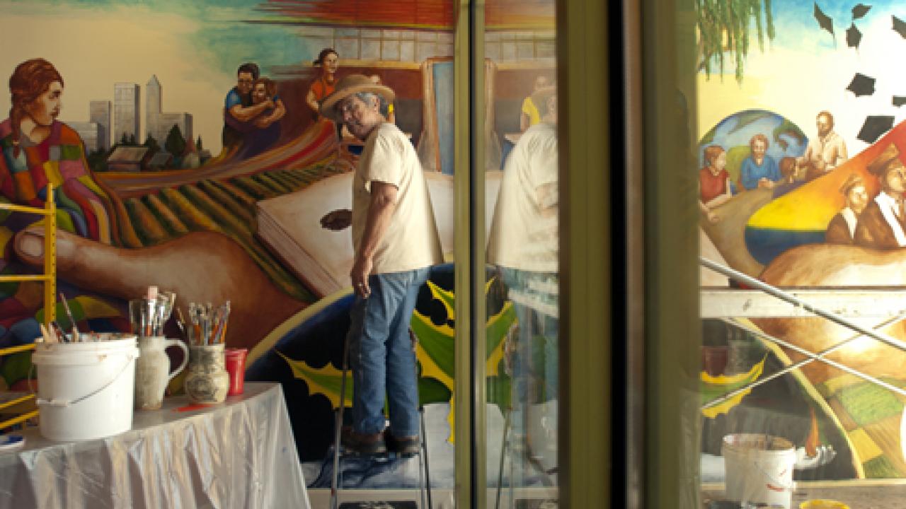 Photo: Professor Emeritus Malaquias Montoya, at work on "The Practice of Freedom" mural
