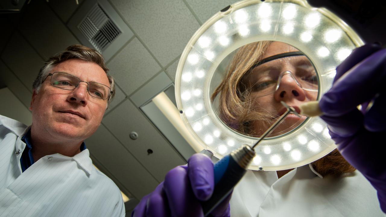 Scientists examine tooth through ring light.