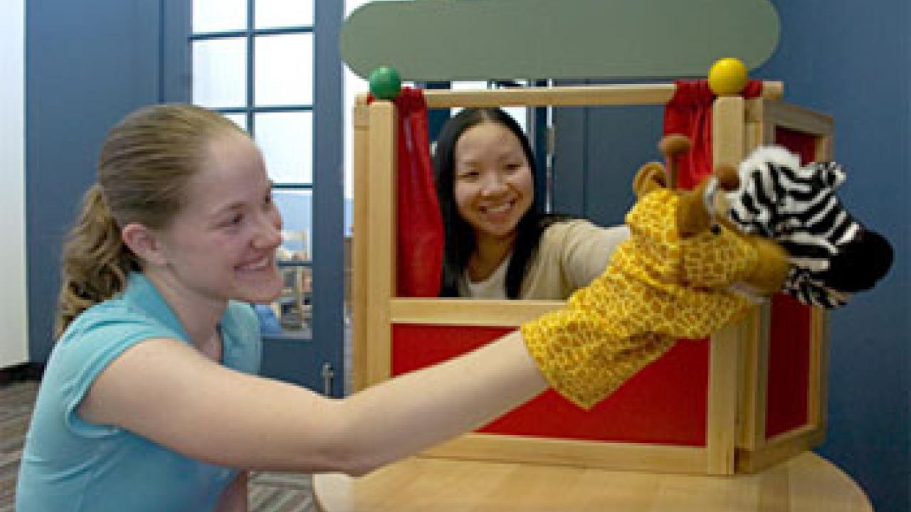 Photo: Two women playing with puppets.