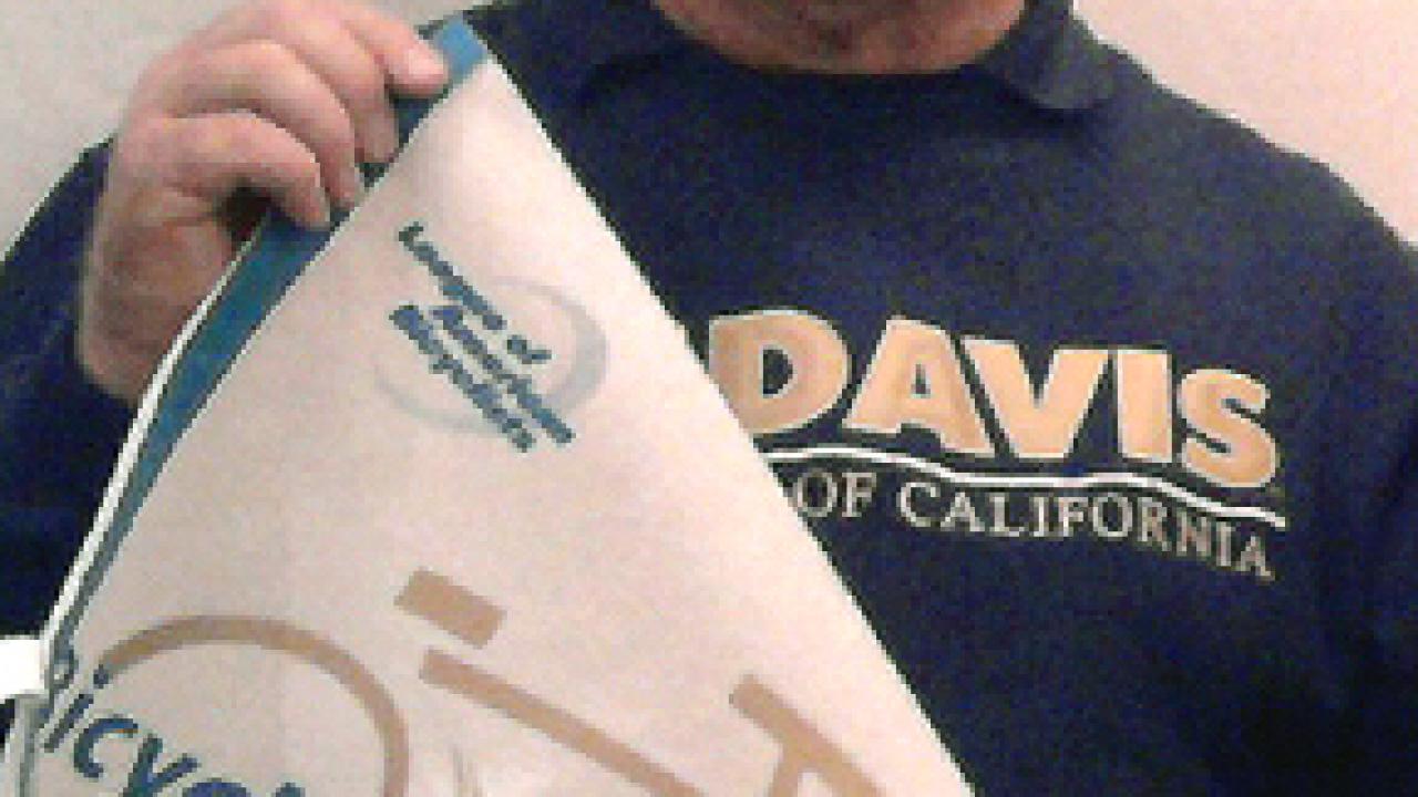 Photo: David Takemoto-Weerts displays the campus's new bicycle-friendly university pennant, after receiving it in Washington, D.C.