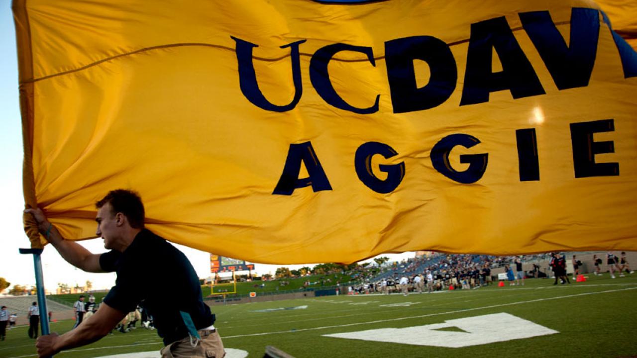 Photo: Man runs into Aggie Stadium carrying giant UC Davs Aggies flag.