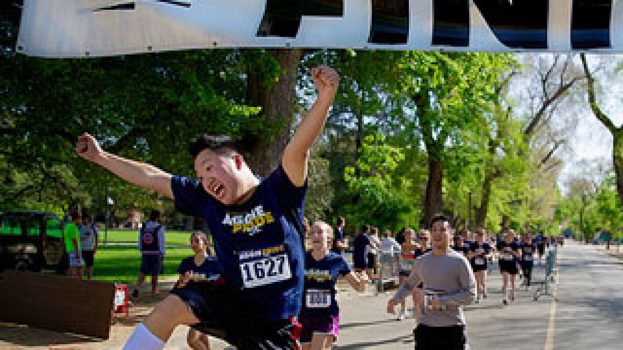Man crossing finish line in s run and jumping for joy
