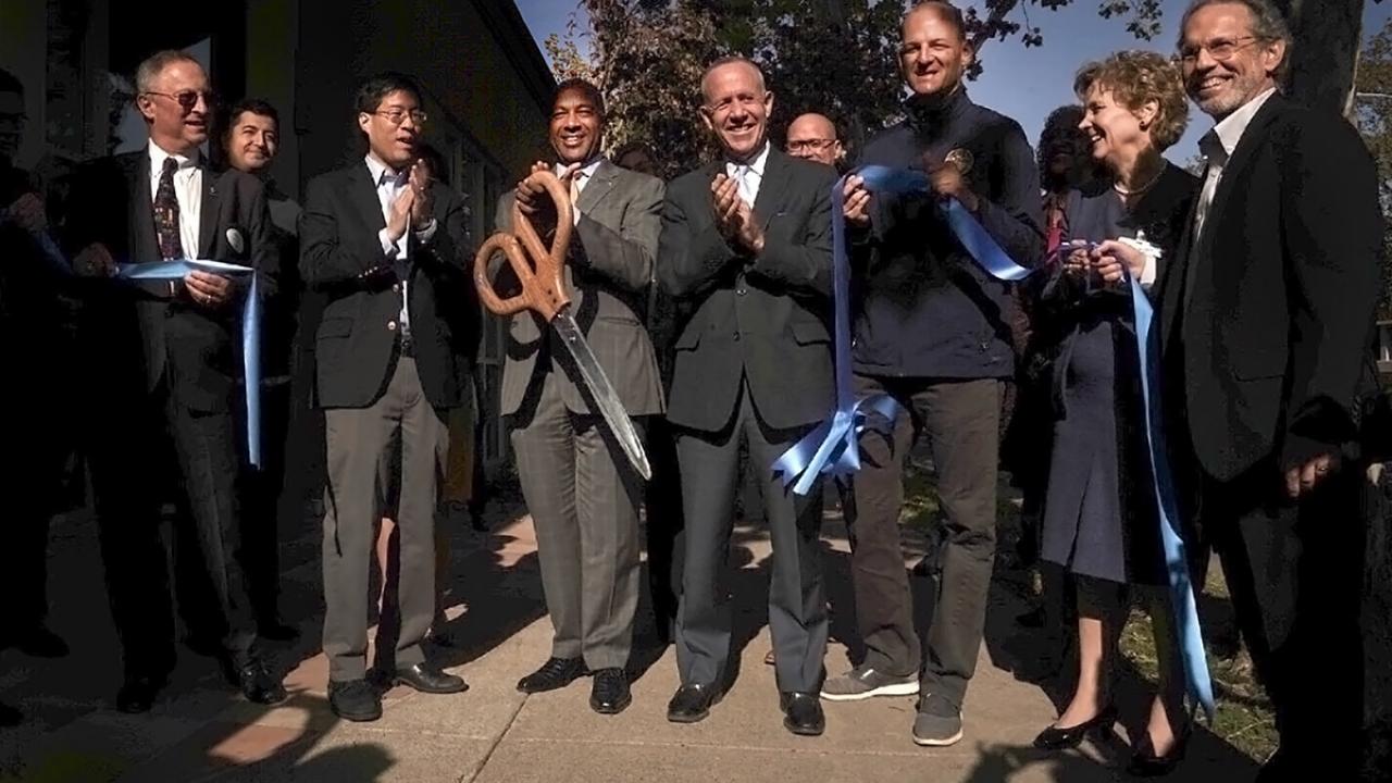 Seven people clap and smile during a ribbon-cutting ceremony.