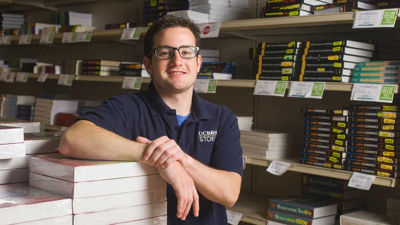 Male student leaning on a stack of books