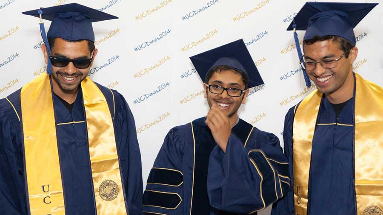 Photo: Three soon-to-be-graduates in UC Davis' new commencement gowns: blue with gold trim