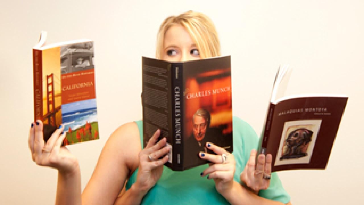 Woman reading three books with four hands