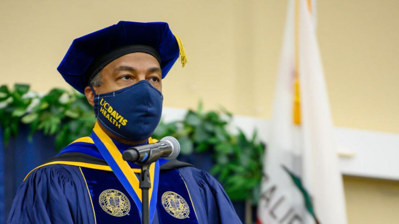 Chancellor Gary S. May in commencement regalia and wearing a UC Davis-branded face mask.