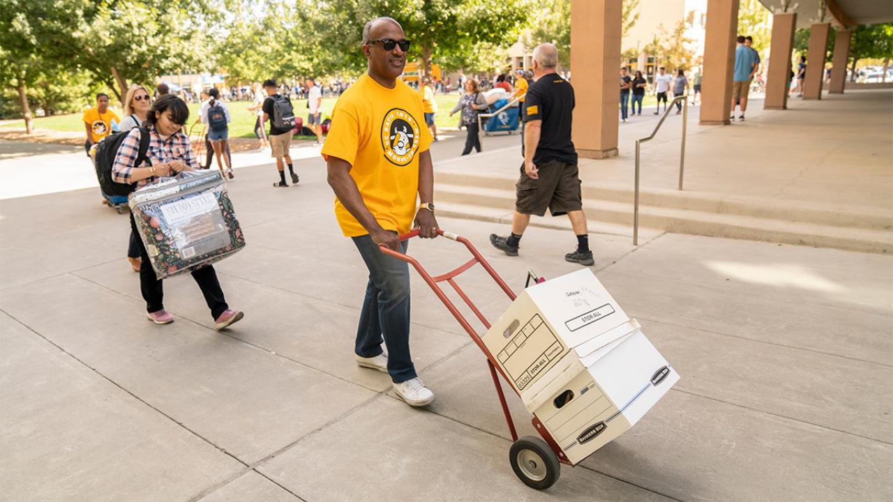 Chancellor Gary S. May moves boxes for a student.