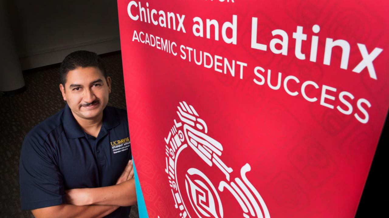 Cirilo Cortez by a banner for the Center for Chicanx and Latinx Academic Student Success