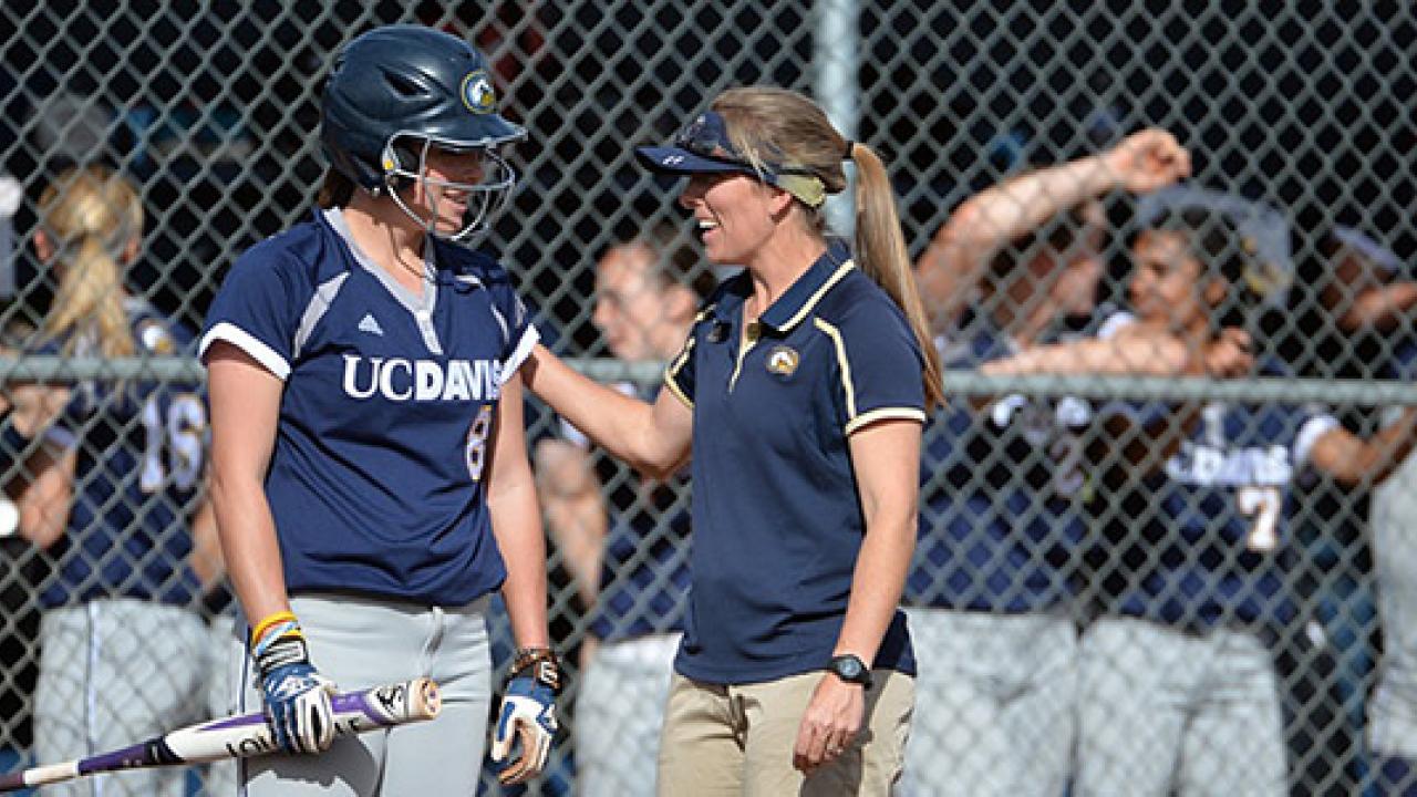 A softball coach, right, talking to a batter in a helmet