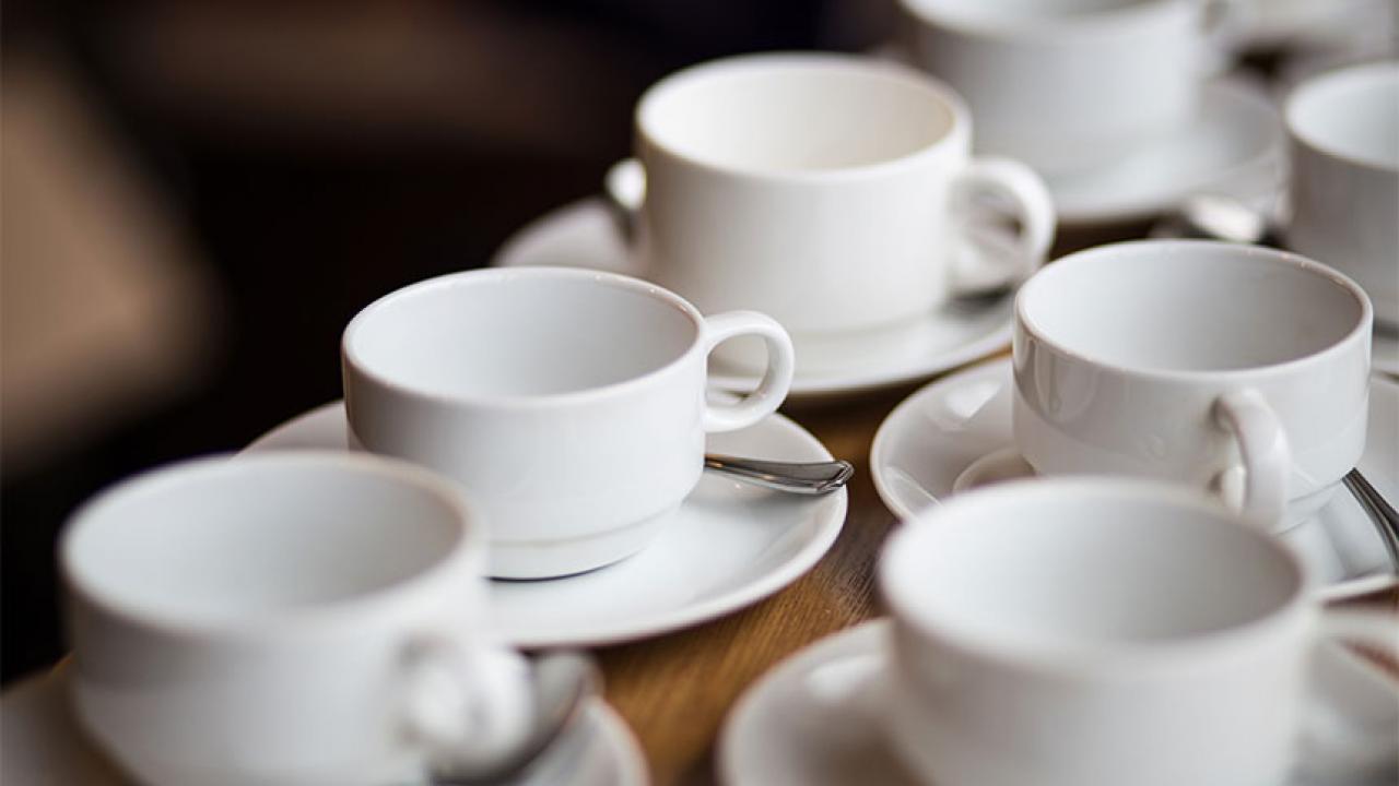 Five white coffee cups and saucers