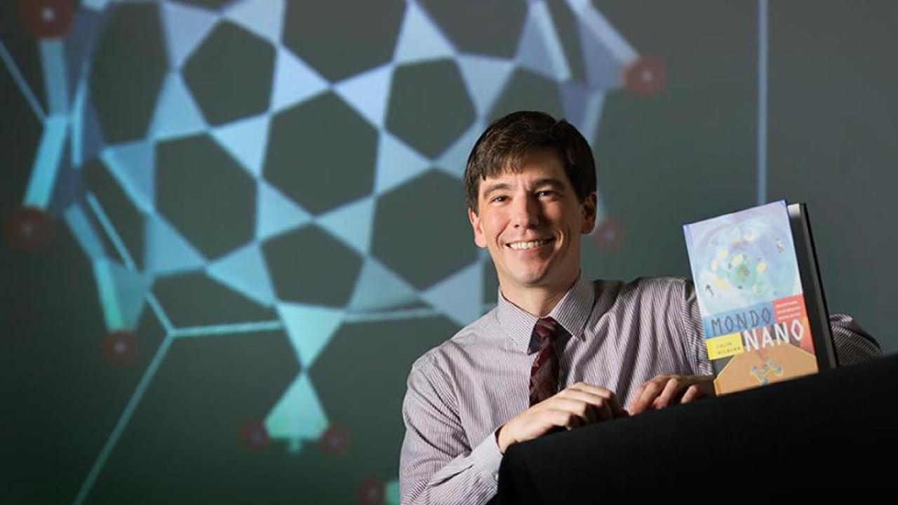 Colin Milburn holds up his book "Mondo Nano: Fun and Games in the World of Digital Matter."