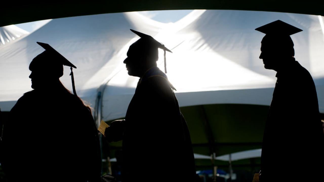 Photo: Three graduates in silhouette