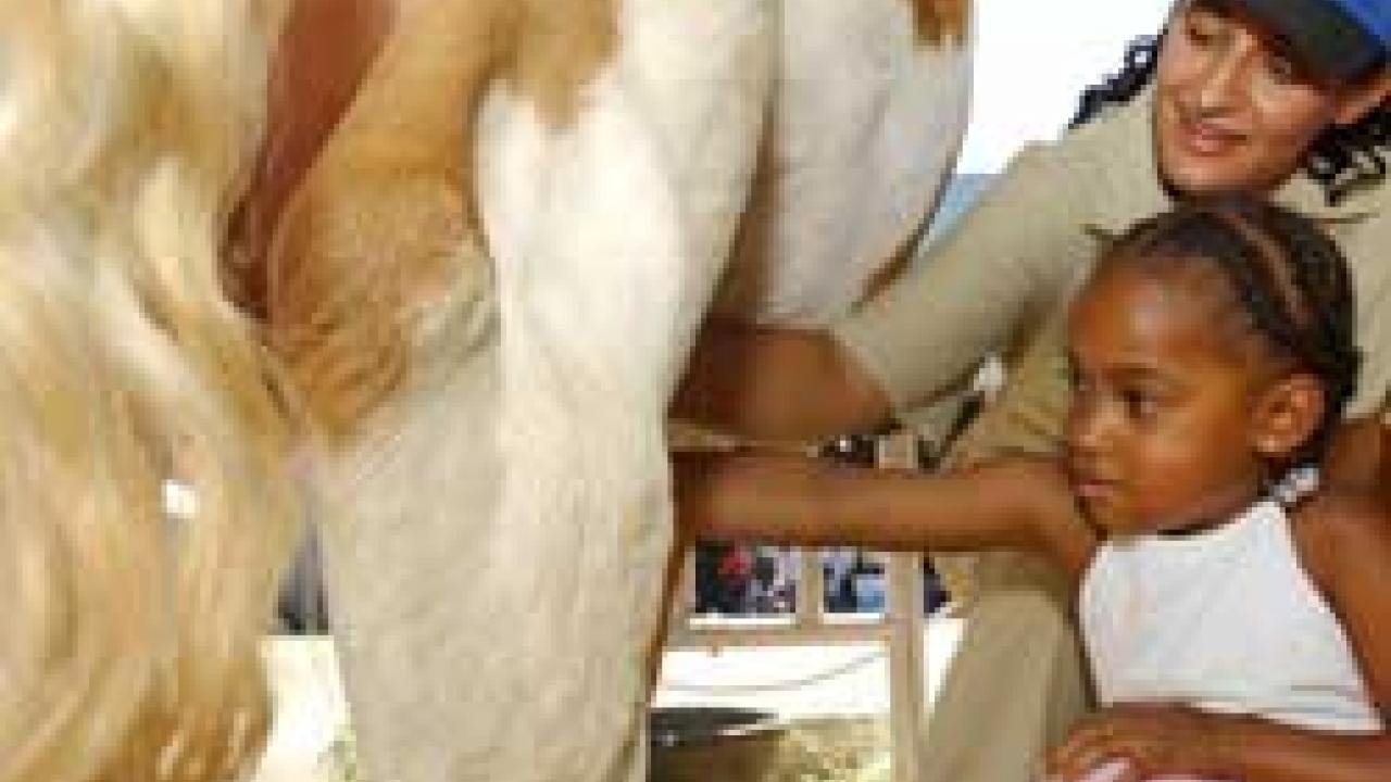 photo of little girl looking at cow's milking apparatus while vet student looks on