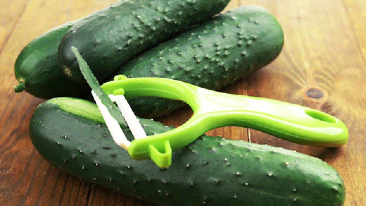 Three cucumbers with a peeler on top