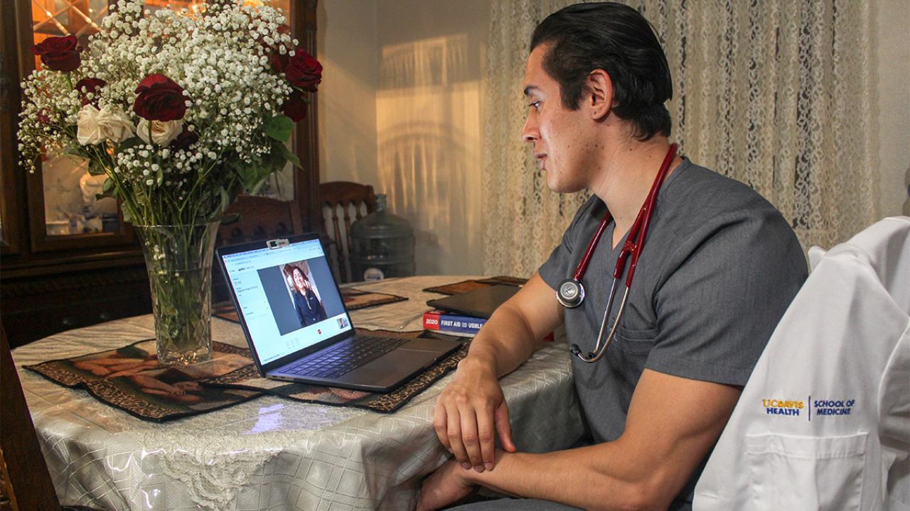 Medical student Dagoberto Pi&ntilde;a speaks to a patient on a laptop.