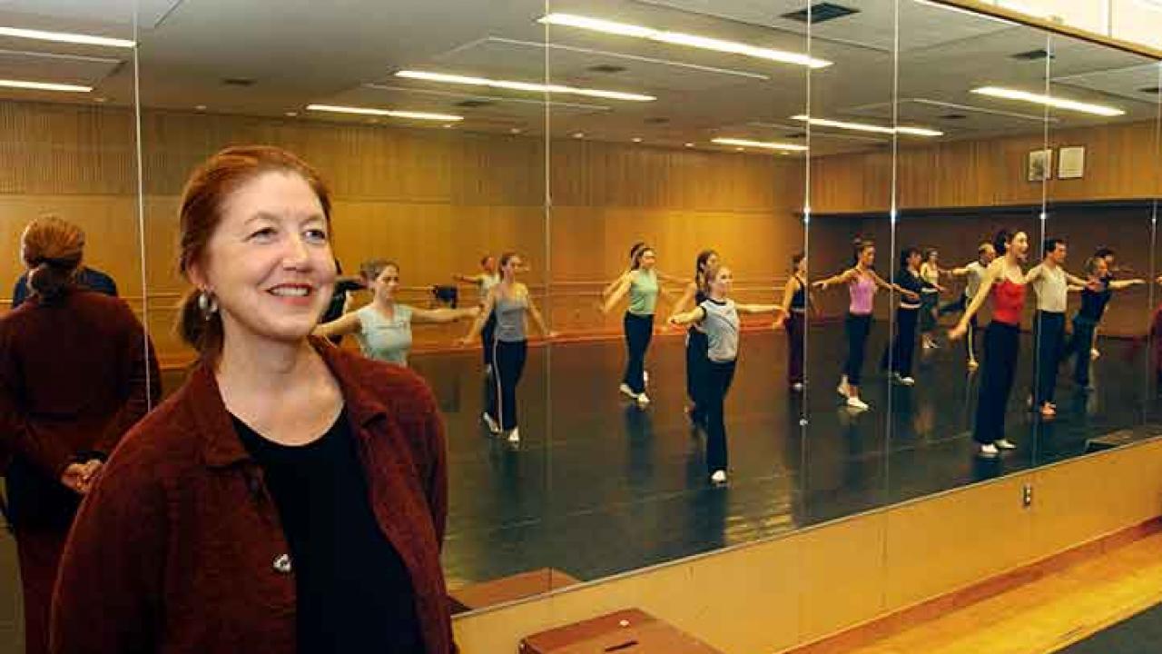 Photo: Professor Della Davidson in dance studio, students in mirror behind her