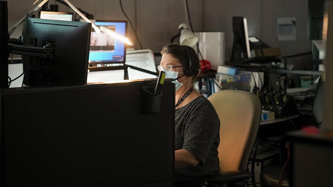 A dispatcher wearing a face covering at her work station