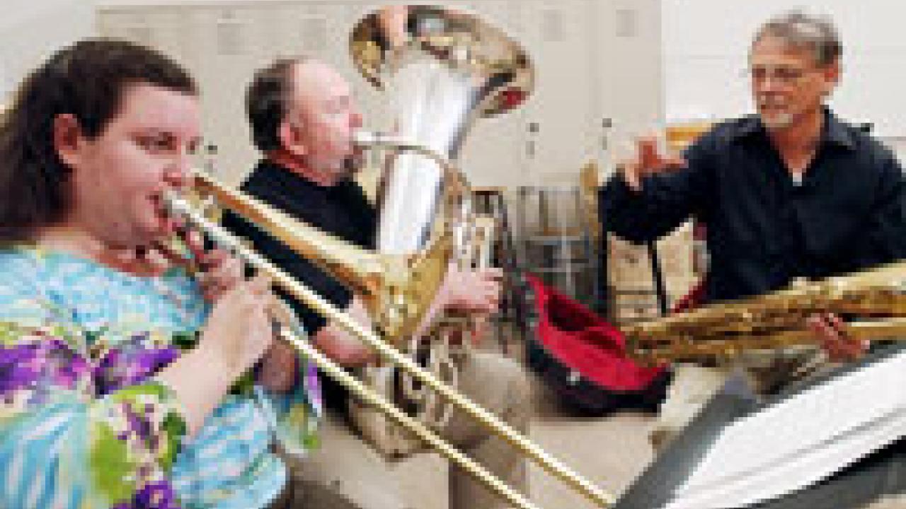 photo of D. Kern Holoman working with musicians Bob Rucker, on the tuba, and Rebecca Brover, on the trombone, who are among those going to France this