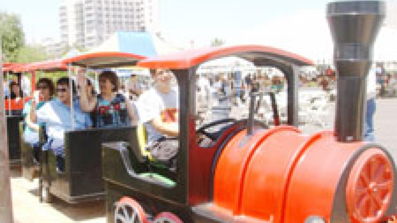 photo of employees riding on a mini train to the Health System TGFS festivities