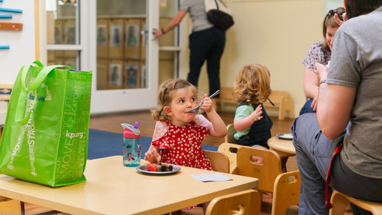 Girl eats cake at table in child care center.