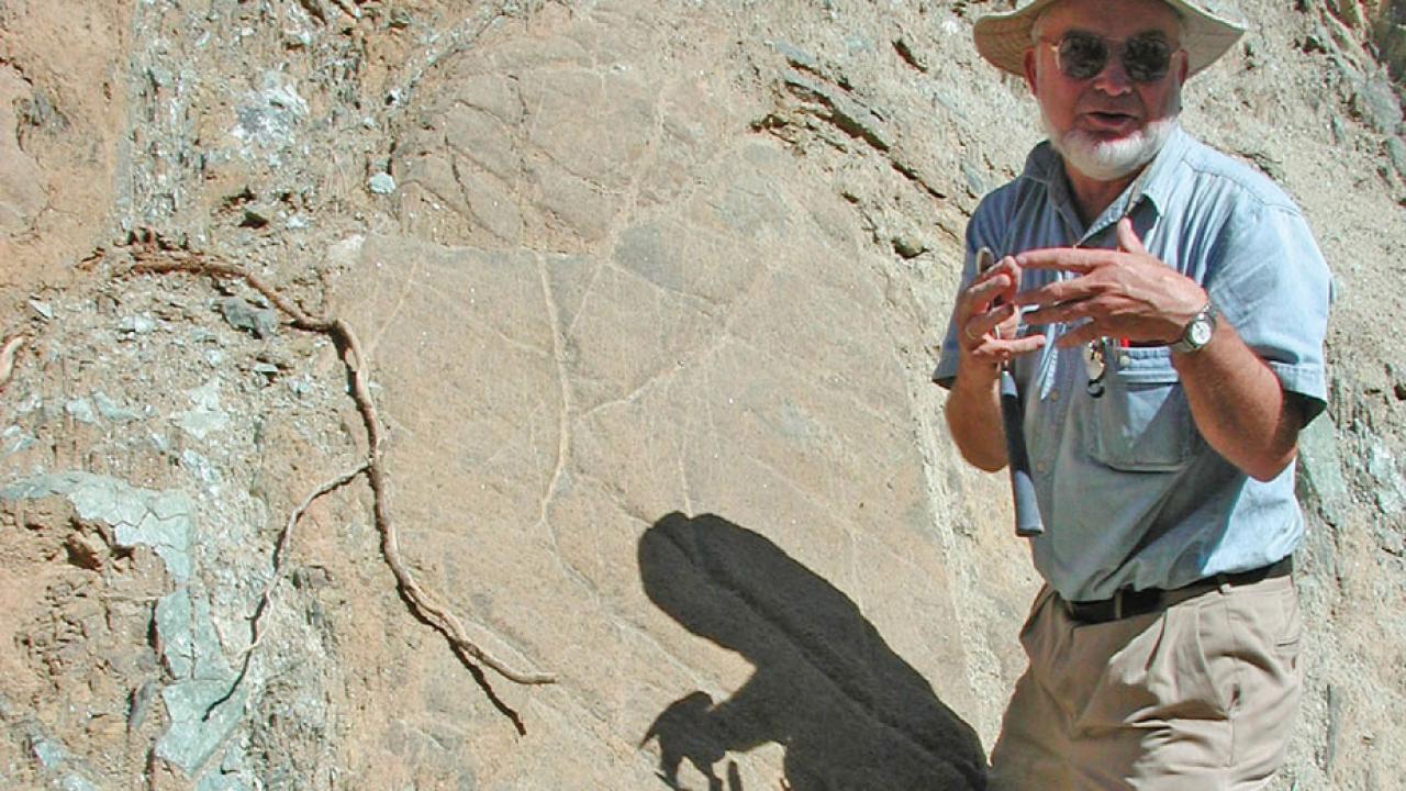 Eldridge Moores gestures in front of a rock face.