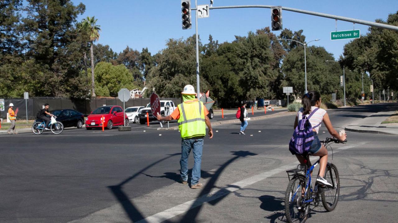 Flagger stops traffic for a bicyclist in crosswalk.