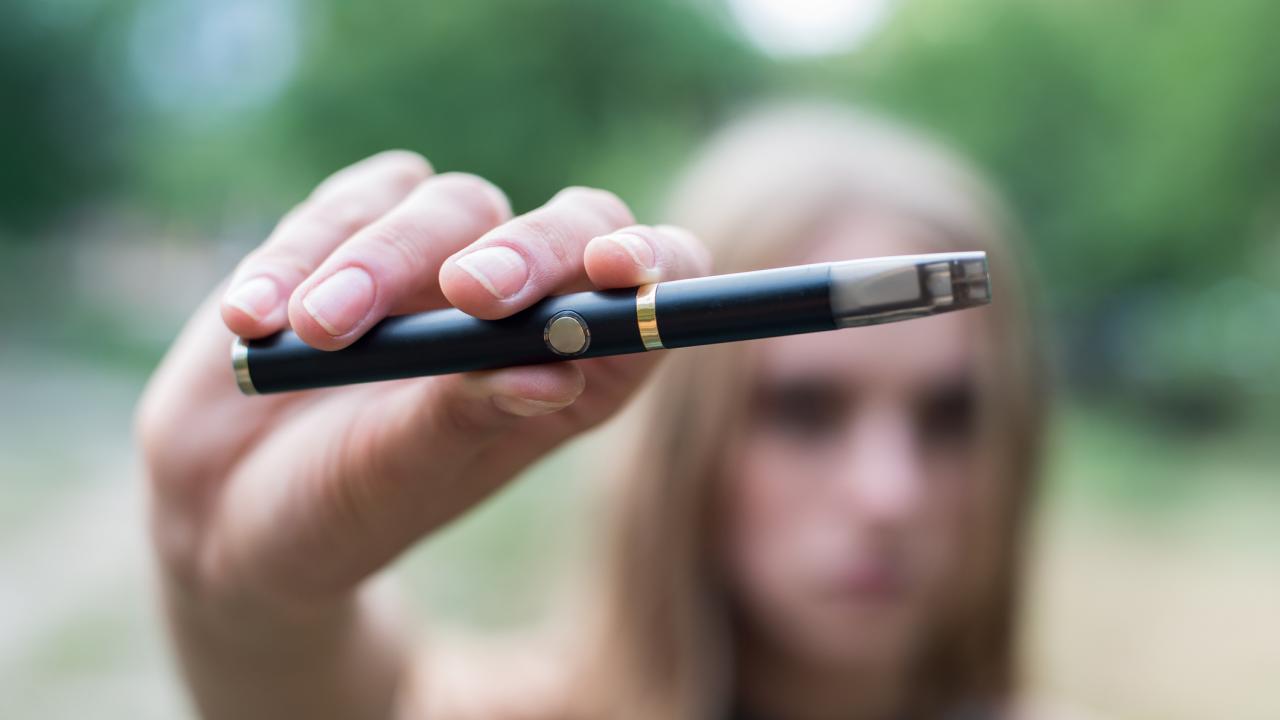 A girl holds an e-cigarette