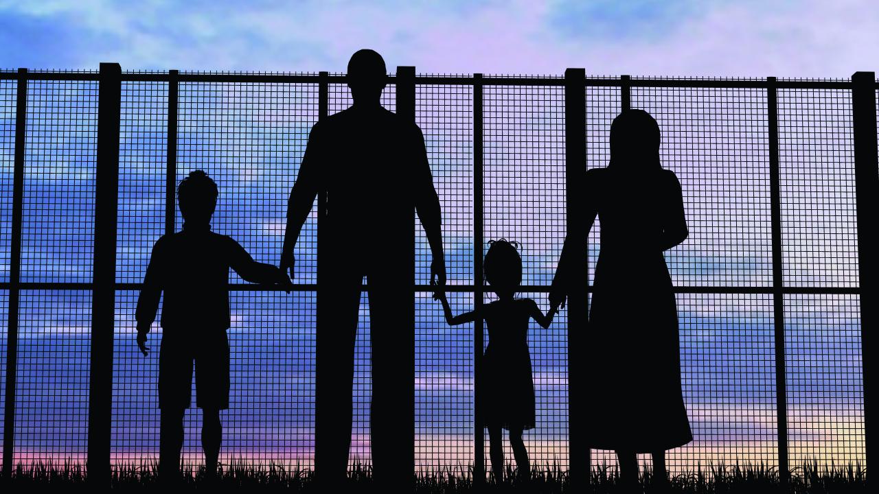 Silhouette of family staring through fence