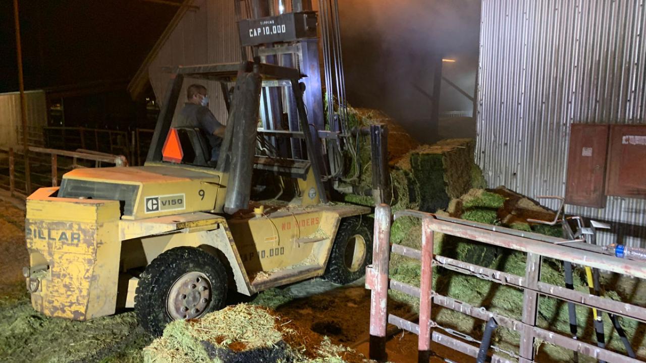 Forklift pulls hay from the fire.