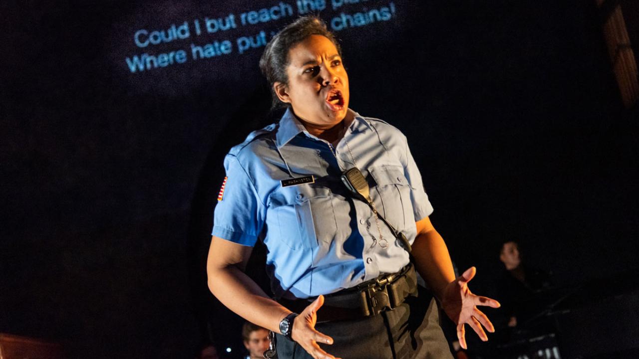 Opera actor in police uniform, singing.